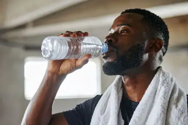Image of man drinking water to improve hydration Royal Tunbridge Wells after work out.